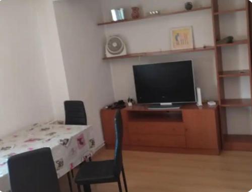 ein Wohnzimmer mit einem TV, einem Tisch und Stühlen in der Unterkunft Sencillo Alcala in Alcalá de Henares