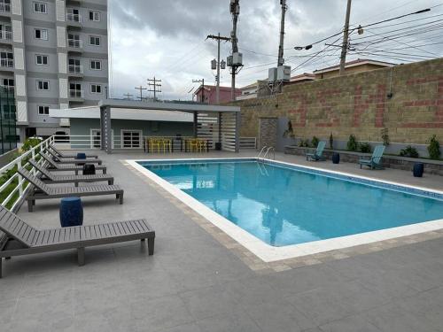a large swimming pool with chairs and a building at Apartamento en Villa Firenze in Tegucigalpa