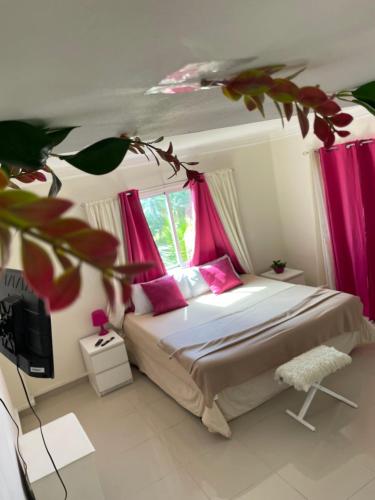 a bedroom with a bed with pink curtains and a tv at Apartamento frente al Mar in La Francia