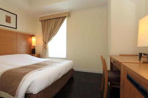 فندق Monterey Lasoeur Ginza في طوكيو: غرفة نوم بسرير ومكتب ونافذة