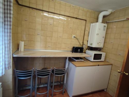 a small kitchen with a counter with a microwave and stools at Coslada parque blanco in Coslada