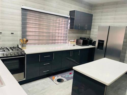 een keuken met zwarte kasten en roestvrijstalen apparatuur bij Executive Home away from Home in Accra