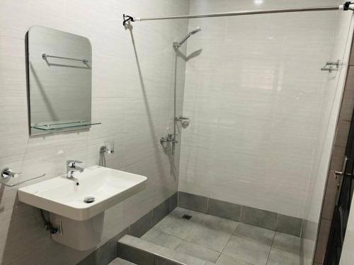 een badkamer met een wastafel en een douche met een spiegel bij Executive Home away from Home in Accra