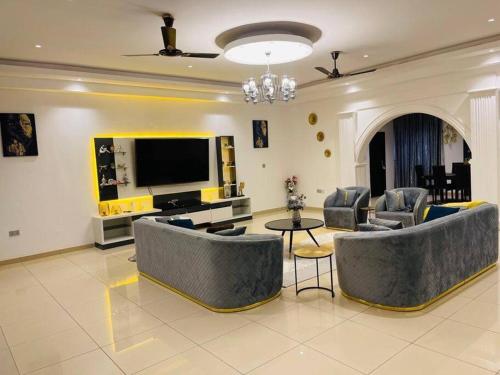 een woonkamer met banken en een flatscreen-tv bij Executive Home away from Home in Accra