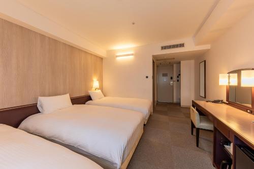 a hotel room with three beds and a television at Court Hotel Asahikawa in Asahikawa