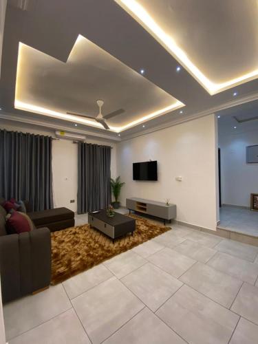 Il comprend un salon doté d'un canapé et d'une télévision à écran plat. dans l'établissement Cozy Lux Apartments by Harolty, à Kumasi