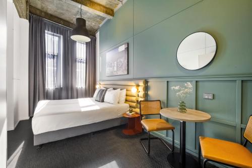 シドニーにあるザ アーバン ニュータウンのベッドとテーブルが備わるホテルルームです。