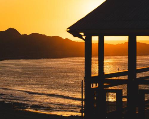 a sunset over the ocean with a building on the beach at Cabaña el Mirador Caleuche. in Ciudad de Chañaral