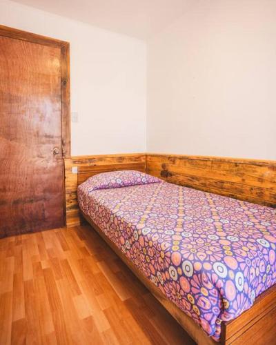 a bedroom with a bed with a wooden headboard at Cabaña el Mirador Caleuche. in Ciudad de Chañaral