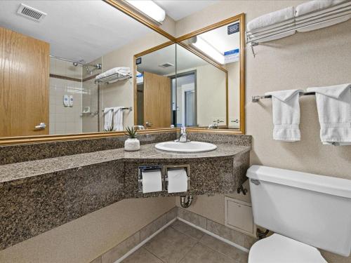 a bathroom with a sink and a toilet and a mirror at Comfort Inn & Suites Downtown Tacoma in Tacoma