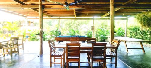 einen großen Holztisch und Stühle auf einer Terrasse in der Unterkunft Encanto Hostel in Guachaca