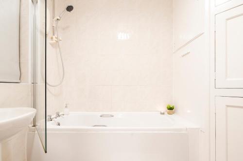 Baño blanco con bañera y lavamanos en Food And Drink Expo 2024, Modern Large House, Minutes from the NEC - Airport Perfect for Contractors, HS2 Staff Fast WIFI AND FREE Parking en Birmingham