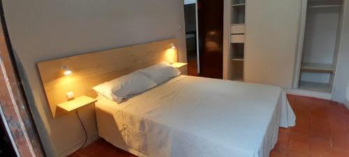 a bedroom with a white bed with a wooden headboard at La Perla in General Alvarado