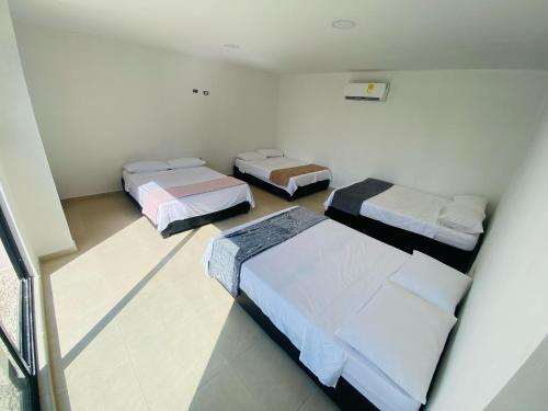 CABAÑA PARA VACACIONAR EN SABANAGRANDE في Sabanagrande: غرفة نوم بثلاث اسرة في غرفة
