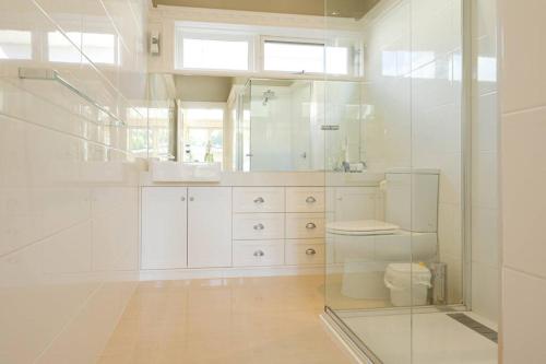 a white bathroom with a toilet and a mirror at By the Beach Coastal Cabin with Hot Tub in Cowes