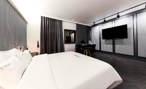 Den Basta hotel في Yangsan: غرفة فندقية بسرير وتلفزيون بشاشة مسطحة