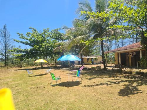 un grupo de sillas y sombrillas en un patio en Casa de veraneio, en Ilha Comprida