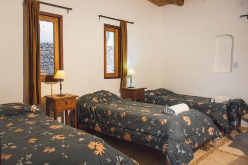 a hotel room with three beds and two windows at Capec Alojamiento in Tilcara
