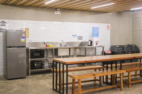 uma cozinha com mesas de madeira e um frigorífico de aço inoxidável em 217 Bonifacio Residences em Baguio