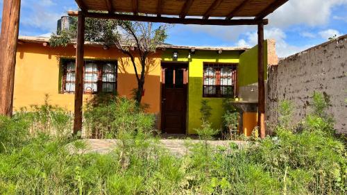 une maison jaune et verte avec une porte dans l'établissement La Casita de la Abuela Huacalera - Quebrada de Humahuaca, à Huacalera