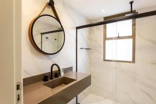a bathroom with a mirror and a sink and a shower at Estúdio aconchegante frontal praia Barra - 2 suítes in Rio de Janeiro