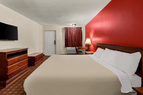 a bedroom with a large bed and a red wall at Rodeway Inn in Dickson