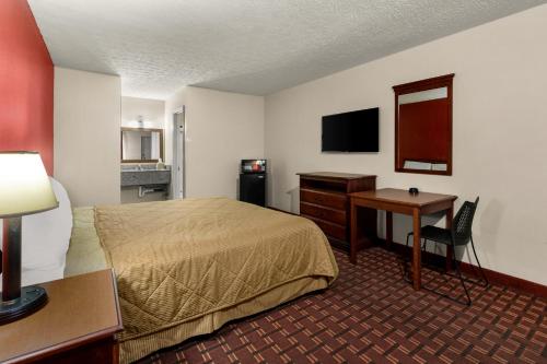 a hotel room with a bed and a desk and a table at Rodeway Inn Dickson in Dickson