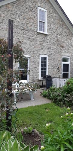 a brick house with a bench in the yard at Stone Carriage House in Picton