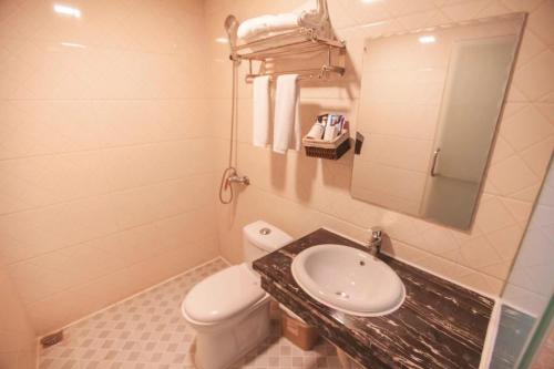 La salle de bains est pourvue d'un lavabo, de toilettes et d'un miroir. dans l'établissement Zhangjiajie Tianmen Mountain Aribadi Inn, à Zhangjiajie