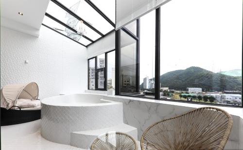 a room with a tub and chairs and windows at Den Basta hotel in Yangsan