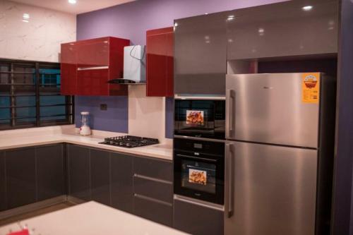 una cocina con nevera de acero inoxidable y armarios rojos en Sleek Luxury Homes, en Kumasi