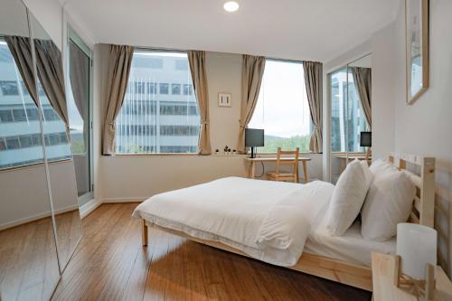 1 dormitorio con 1 cama blanca grande y ventanas grandes en Central 2-Bed with Gym and Secure Parking, en Canberra