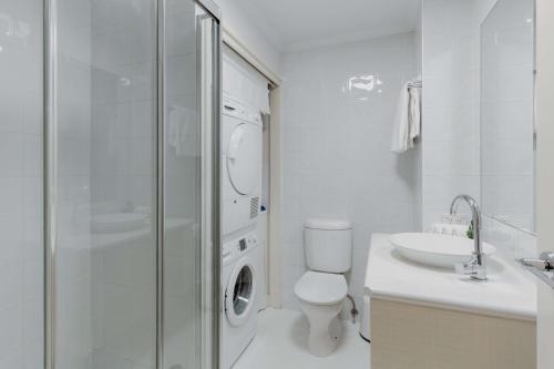 Baño blanco con aseo y lavamanos en Central 2-Bed with Gym and Secure Parking, en Canberra