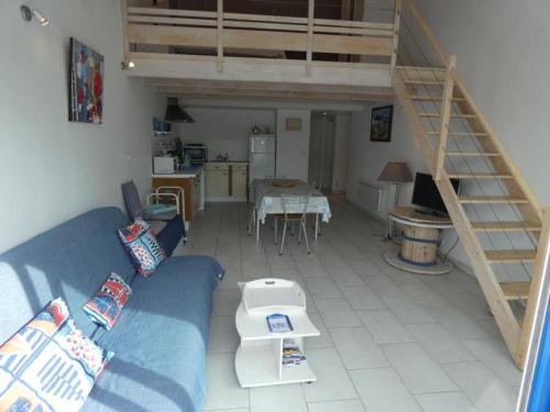 un salon avec un canapé bleu et une cuisine dans l'établissement Appartement spacieux avec balcon, à 100m de la plage - Notre-Dame-de-Monts - FR-1-540-213, à Notre-Dame-de-Monts