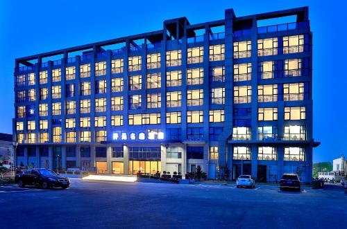 舟山市にあるZhoushan Maison New Century Hotelの駐車場車を停めた大きな建物