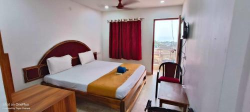 a bedroom with a bed and a window with a red curtain at SRIKRUTI SEA VIEW in Puri