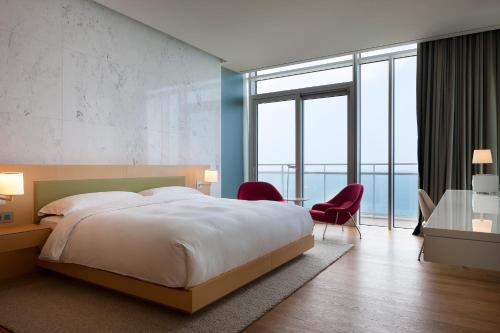 a bedroom with a large bed and a desk and chairs at SEAMARQ HOTEL in Gangneung