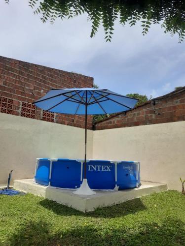 a table with an umbrella and two blue chairs at Casa Alto da Falésia in Baía Formosa