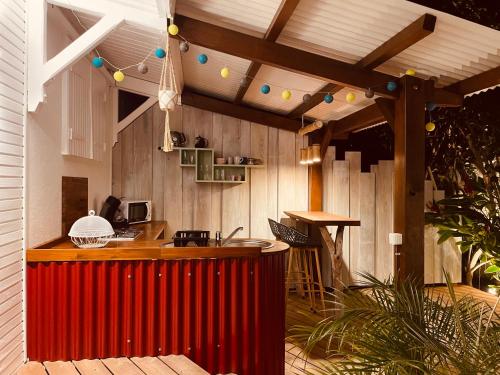 an outdoor kitchen with a red bar and a wooden wall at Les Coulirooms - Suite avec jacuzzi et grande terrasse in Sainte-Anne
