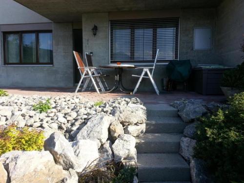 a patio with a table and chairs and rocks at Elfe-Apartments Two-room Apartment with Garden, 2-4 guests in Emmetten