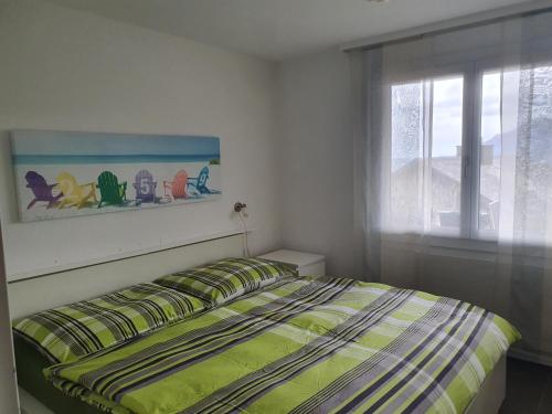 1 dormitorio con 1 cama con ventana y colcha en Elfe-Apartments Two-room Apartment with Garden, 2-4 guests, en Emmetten