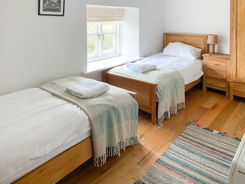 a bedroom with two beds and a window at Murton Cottage in East Ord