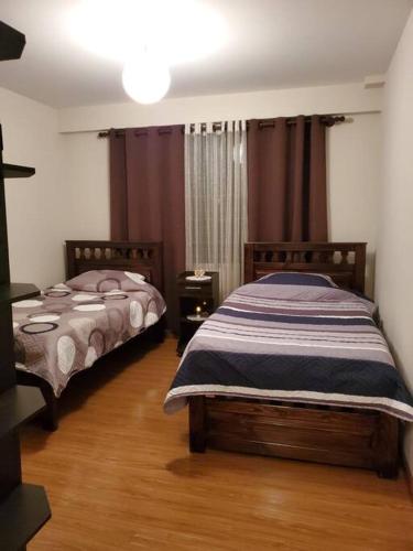 a bedroom with two beds and a wooden floor at Apartamentos La Floresta in Cochabamba