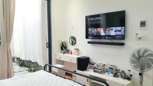 a bedroom with a tv on the wall and a bed at ngaunhien's house - Homestay in Thôn Dư Khánh