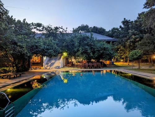a swimming pool with blue water in a yard at Pinthaliya Resort in Sigiriya