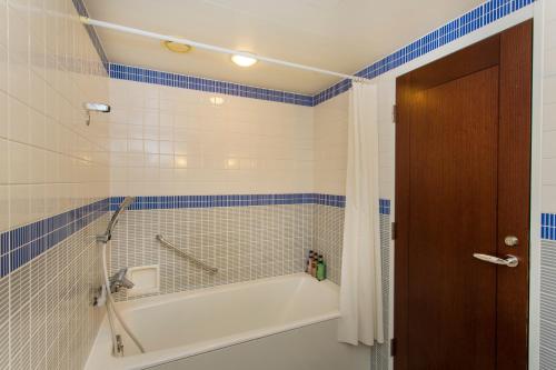 a bathroom with a tub and blue and white tiles at Hotel Monterey Ginza in Tokyo