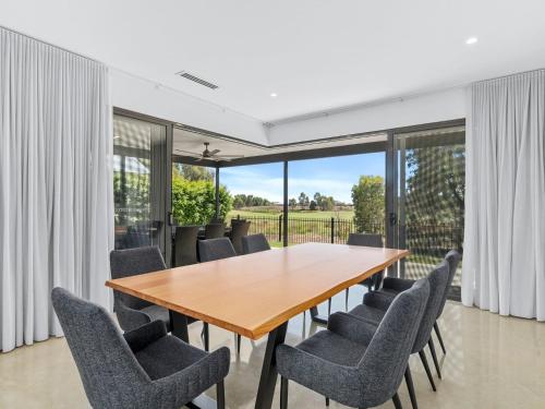 an open dining room with a wooden table and chairs at 45 On Fairway in Yarrawonga
