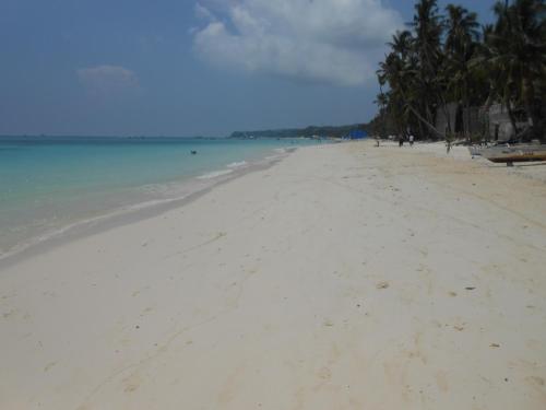 a sandy beach with palm trees and the ocean at Anahaw Apartments Whitebeach in Boracay