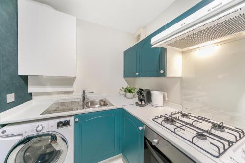 a kitchen with blue cabinets and a washing machine at Strawberry Bank Apartment ✪ Grampian Lettings Ltd in Aberdeen