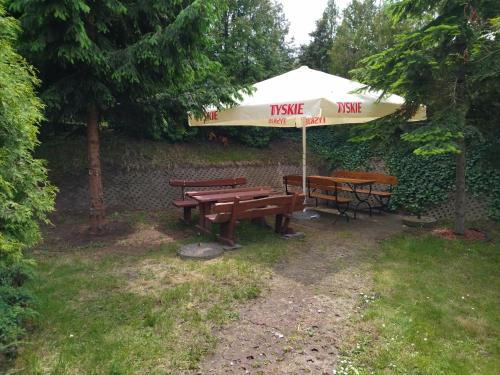 een picknicktafel met een paraplu en twee banken bij Dom na Cichej in Krynica Morska